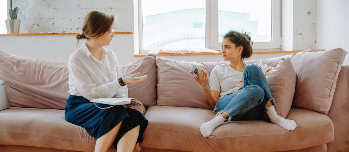 Distressed woman sitting on the couch while talking with her therapist.
