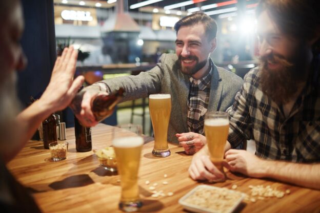Man refusing another drinking while drinking with his friends.