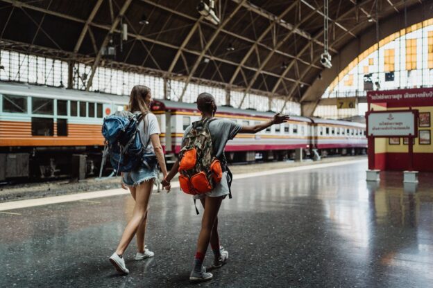 Two girls walking around a train station while on a trip.