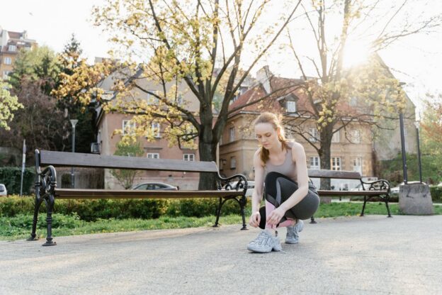 Woman tying her shoes while having a walk in the park.