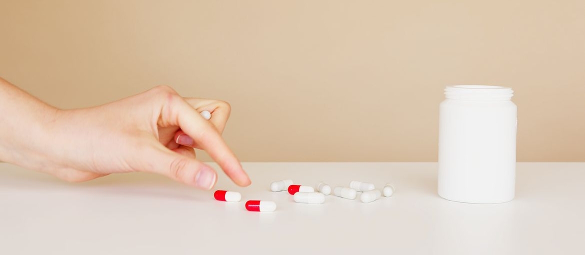 Person picking up a pill from the table.