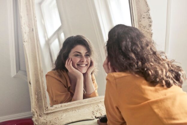 Woman smiling while looking at herself in the mirror.